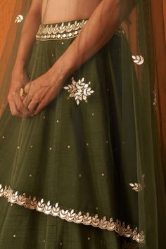 Features an olive green lehenga in raw silk embellished with sequins and mirror work encrusted with gold thread work along the border. Paired with a deep sweetheart neckline embellished bustier with tassel tie-up at the back. This look is completed with an embellished net dupatta.Composition : Lehenga & Blouse: Raw Silk, Dupatta: Net, Lining: CrepeCare: Dry Clean Only and Vacuum Storage All products can be customised for sleeves, length of blouse and neck design Delivery : 6-8 weeks as the product is hand crafted. Check Size Guide or choose MySize for free customisation (All Sizes above XL can be made at 15% additional cost) For more information and sizes please contact fabiliciousfashion@gmail.com or visit our Copenhagen studio.About the Designer : Angad Singh's journey in the world of fa Festive Pista Green Anarkali Set With Sequins, Pista Green Anarkali Set With Sequins, Traditional Embellished Pista Green Anarkali Set, Festive Pista Green Sequined Choli, Festive Green Embellished Sharara, Festive Embellished Green Sharara, Green Raw Silk Anarkali Set With Mirror Work, Green Embellished Lehenga For Festivals, Embellished Green Lehenga For Festive Occasions