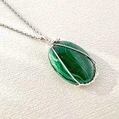 "Malachite Cabochon Necklace Elegantly Wire-Wrapped in Sterling Silver 💎  Details: Gemstones: Malachite Gemstone dimensions: 0.8\"-1.2\" (20-30 mm)  Material: 925 Sterling Silver Total necklace length: 18\" /45 cm Please note 🔹 While you're checking out the photos, remember that each gemstone is like a fingerprint - totally unique. Colors and shapes play differently in each piece, making them one-of-a-kind.  Our pics are snapped under some bold lights to highlight their beauty, but your actual piece might have its own little variations. Caring for gemstones ✨ Wait for your body lotions and perfumes to set in before you put on your jewelry. Ensure your jewelry is stored in a dry environment. We suggest removing your jewelry before working out, taking a bath, or swimming. Keep the Mohs sca Wrapped Gemstone Necklace, Hand Wrapped Green Sterling Silver Jewelry, Wire Wrapped Green Sterling Silver Jewelry, Green Sterling Silver Wire Wrapped Jewelry, Green Wire Wrapped Sterling Silver Jewelry, Green Agate Hand-wrapped Necklaces, Green Agate Hand Wrapped Necklaces, Silver Malachite Gemstone Necklace, Green Hand Wrapped Agate Necklaces