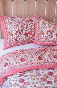 a bed with pink and white pillows on top of it