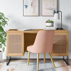 a pink chair sitting in front of a wooden desk next to a potted plant