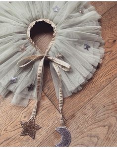 a tutu with a star and moon decoration hanging from it's side on a wooden floor