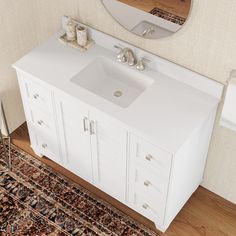 a white bathroom sink sitting on top of a wooden floor next to a wall mounted mirror