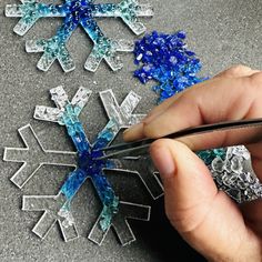 someone is cutting glass snowflakes with scissors