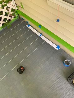 two toy cars are parked on the floor in front of a house that is painted green and white