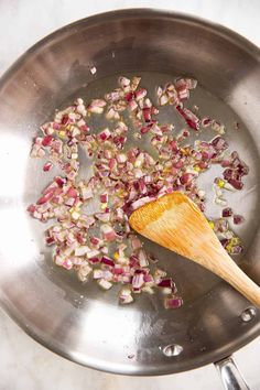 onions being cooked in a frying pan with a wooden spoon