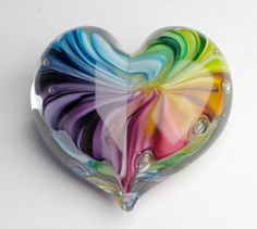 a colorful heart shaped glass object sitting on top of a table next to a white wall