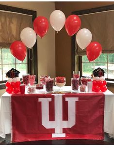 the table is set up with red and white balloons, candy bars, and desserts