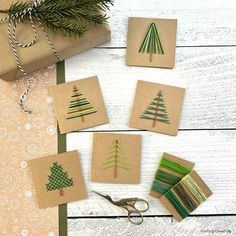 some crafting supplies are laying out on a white wooden table with pine trees drawn on them