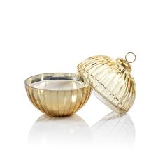 an empty glass bowl next to a golden container on a white surface with reflection in it