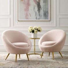 two pink chairs sitting next to each other in front of a painting