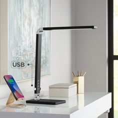 a desk lamp sitting on top of a white table next to a phone and other items