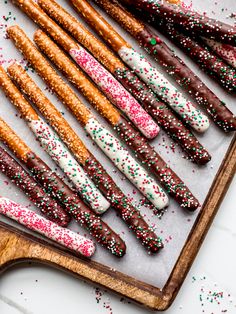 an assortment of pretzels with sprinkles and chocolate on a cutting board