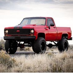 a red pick up truck parked on top of a field