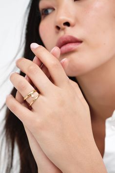 Our Mandy Abstract Ring is an emblem of elegance. Handcrafted from brass with 18k gold plating, this asymmetrical ring coils twice around your finger and presents a luminous faux pearl between her bands. Delicate and expressive, modern and timeless, Mandy raises the standard for your capsule jewelry box. Each ring includes a Marcella-branded vegan leather travel case for safe storage and easy travel.[SPLIT] Available in one size. Approximately .75” (2 cm) in height, and 1" (2.25 cm) in width. 18 Gold Plated Open Pearl Ring, Gold Open Pearl Ring With Metal Band, Gold Minimalist Pearl Ring, Minimalist Gold Pearl Ring With Detail, Rose Gold Open Pearl Ring, Gold Open Ring Pearl Fine Jewelry, Gold Pearl Open Ring For Promise, Yellow Gold Open Pearl Ring, Capsule Jewelry