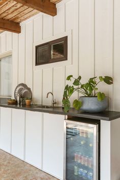 a kitchen with white cabinets and black counter tops next to a plant in a blue vase