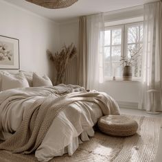 a large bed sitting in a bedroom next to a window with drapes on the windowsill