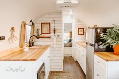 the interior of a tiny home with wood counter tops and white cabinets, along with wooden flooring