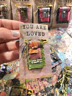 a person holding up a card with some small pieces of fabric on it and the words you are loved