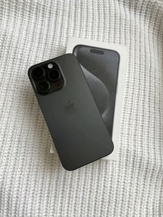 two iphones are sitting next to each other on a bed, one is black and the other is gray