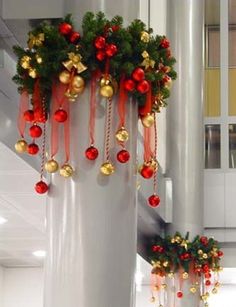 christmas decorations hanging from the side of a pole in an office building with red and gold ornaments