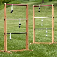 two wooden racks with balls hanging from them in the middle of a grassy area next to some trees