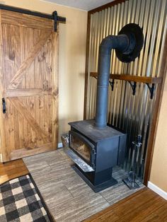 a wood burning stove sitting inside of a living room next to a wooden door and rug