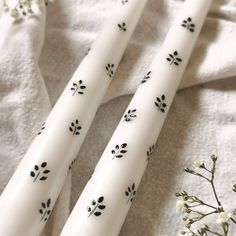 two white candles with black designs on them