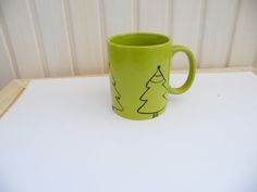 a green coffee mug sitting on top of a white table