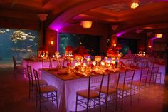 a dining room set up for a party with candles and fish tank in the background