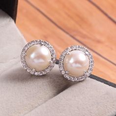 This Sterling Silver Earring features an Elegant Art With Natural Pearl Gemstone surrounded by tiny Zircon Gemstones. The cavity is made from genuine solid 925/92.5 Sterling silver and stamped as S925. This Jewelry is Lead free and finished with Rhodium to resist scratches and tarnish. ITEM DESCRIPTION Item Code: JAER278/21 Metal: 925/92.5 Sterling Silver Gemstone: Natural Pearl Gemstone Shape: Round Gemstone Size: 9 x 9 MM Surrounded Stones: Zircon Earring Length: 12 MM Earring width: 12 MM Wei White Gold Gemstone Round Earrings, White Gold Earrings With Gemstones, Classic Pearl Earrings With Halo Design For Gifts, Diamond White Sterling Silver Pearl Earrings For Anniversary, Diamond White Pearl Earrings In Sterling Silver For Anniversary, Cubic Zirconia Pearl Earrings As Gift, Halo Setting Earrings Fine Jewelry As Gift, Gift Round Pearl Earrings With Cubic Zirconia, Sterling Silver Gemstone Round Bridal Earrings