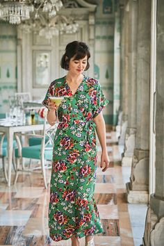 a woman in a green floral dress holding a plate