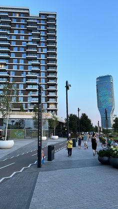 people are walking on the sidewalk in front of tall buildings