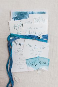 three pieces of paper with blue and white ink on them, tied together in twine