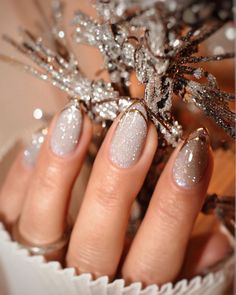 Shimmering silver nails are elevated with a delicate touch of gold at the tips, creating an enchanting and sophisticated look. The glitter finish catches the light beautifully, giving these almond-shaped nails a frosted effect perfect for New Year's festivities. This design combines subtle sparkle with an understated golden detail, adding a hint of luxury to any celebration outfit. Blue Christmas Nails, Holiday Nails Winter, New Years Nail Designs, New Years Eve Nails, Holiday Nail Designs, Party Nails, Blue Nail, Sparkle Nails, Nail Styles