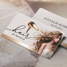 two business cards with hair products on them sitting next to each other in front of a marble background