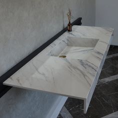 a white marble sink sitting on top of a counter next to a vase with flowers