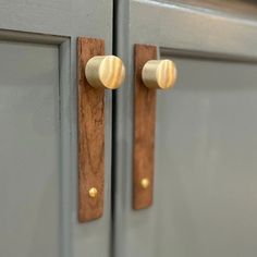 two brass knobs are on the handles of gray cabinets with gold hardware and wood accents