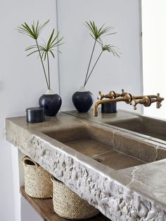 two black vases sitting on top of a stone sink