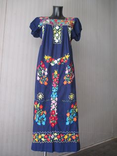 "Beautiful 70s Oaxacan blue dress. Made in Mexico. Ethnic dress. Cotton. Sumptuously hand embroidered (pic.7), with colourful bunches of flowers in front and all around the square neckline (pics 2-5). The short sleeves are gathered with an elastic (pics 2-4-5). Side vents (pic.4). Ankle length (pic.1). Loose fittng. Mint conditions. It seems never been worn. It can fit size S-M Measurements: (lay flat and double chest and hips) Shoulders 15.7\"/40 cms chest 39.3\"/100 cms hips up to 47.2\"/ fino Traditional Blue Fiesta Dress, Folk Style Blue Short Sleeve Dress, Blue Folk Style Short Sleeve Dress, Blue Short Sleeve Folk Dress, Blue Folk Dress With Short Sleeves, Blue Short Sleeve Festival Dress, Folk Style Embroidered Short Sleeve Dress, Multicolor Short Sleeve Embroidered Dress For Cinco De Mayo, Traditional Short Sleeve Dress For Fiesta