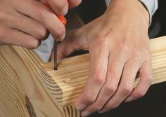 two hands are working on a piece of wood