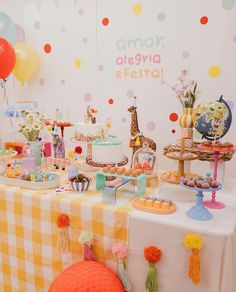 a table topped with lots of cakes and desserts covered in colorful paper pom poms