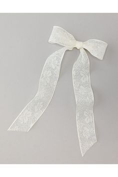 a white ribbon with flowers and leaves on the side, tied in a bow tie