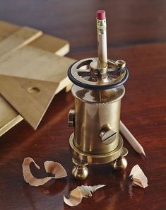 a pencil is sitting on top of an old fashioned coffee grinder with broken pieces of paper around it