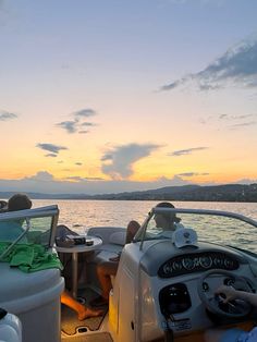 two people sitting in the back of a boat at sunset