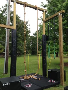 an outdoor gym set up in the middle of a park with ropes hanging from it