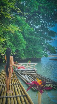 a woman walking across a bamboo bridge over water