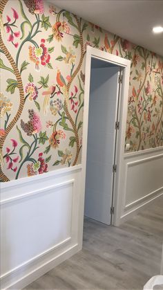 an empty room with floral wallpaper on the walls and door to another room in the background