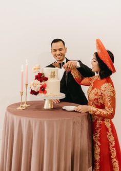 a man and woman standing next to a table with a cake in front of them