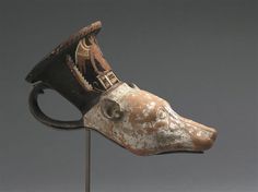 an ancient mask is on top of a metal stand with a black hat on it's head