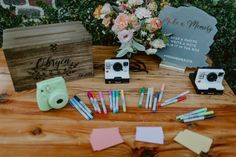 several polaroid cameras sitting on top of a wooden table next to post it notes